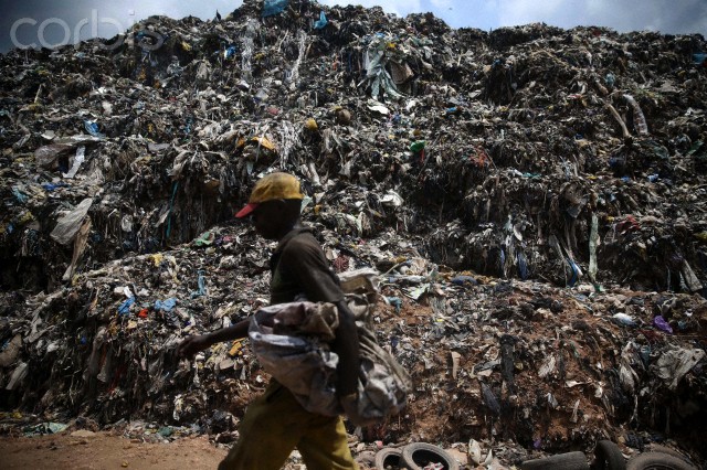 11 Oct 2013, Lagos, Nigeria --- A scavenger walks past a heap of rubbish at Olusosun waste dump site in Ojota district in Lagos October 10, 2013. One thing Nigeria's megacity of Lagos, one of the world's largest, generates in abundance is trash. Now it plans to turn that rubbish into electricity which the city desperately lacks. Picture taken October 10, 2013. REUTERS/Akintunde Akinleye (NIGERIA - Tags: ENVIRONMENT ENERGY) --- Image by © AKINTUNDE AKINLEYE/Reuters/Corbis